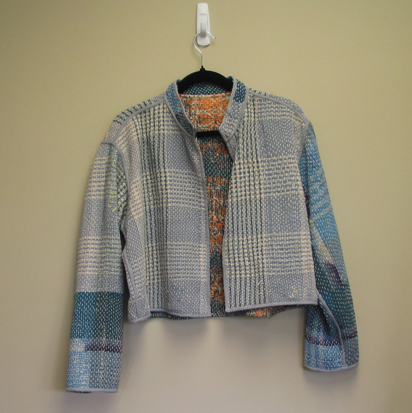 Plaid jacket on a hanger against a plain background