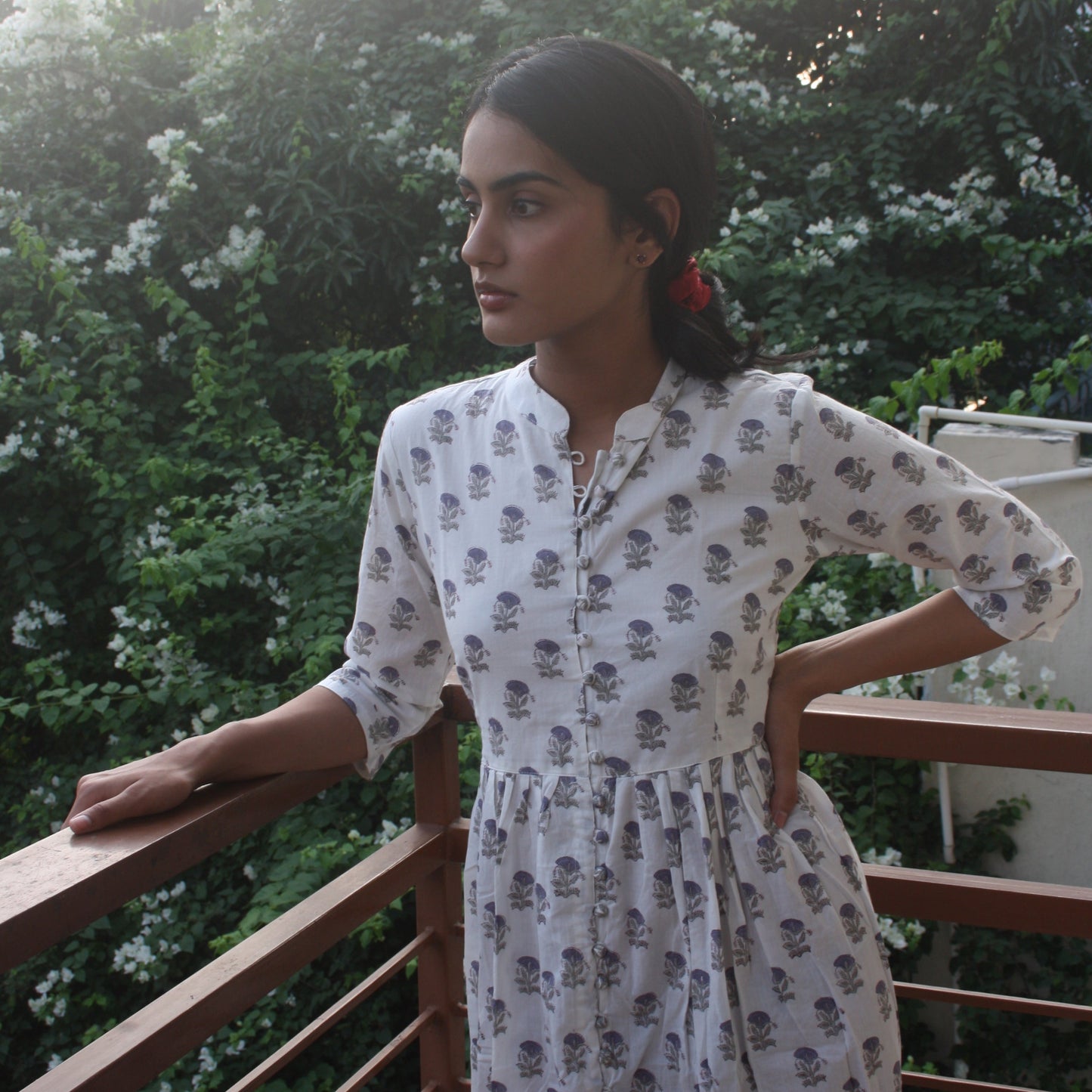 Woman in a floral dress standing outdoors with greenery in the background