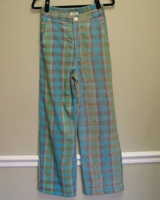 Plaid-patterned pants on a hanger against a beige wall