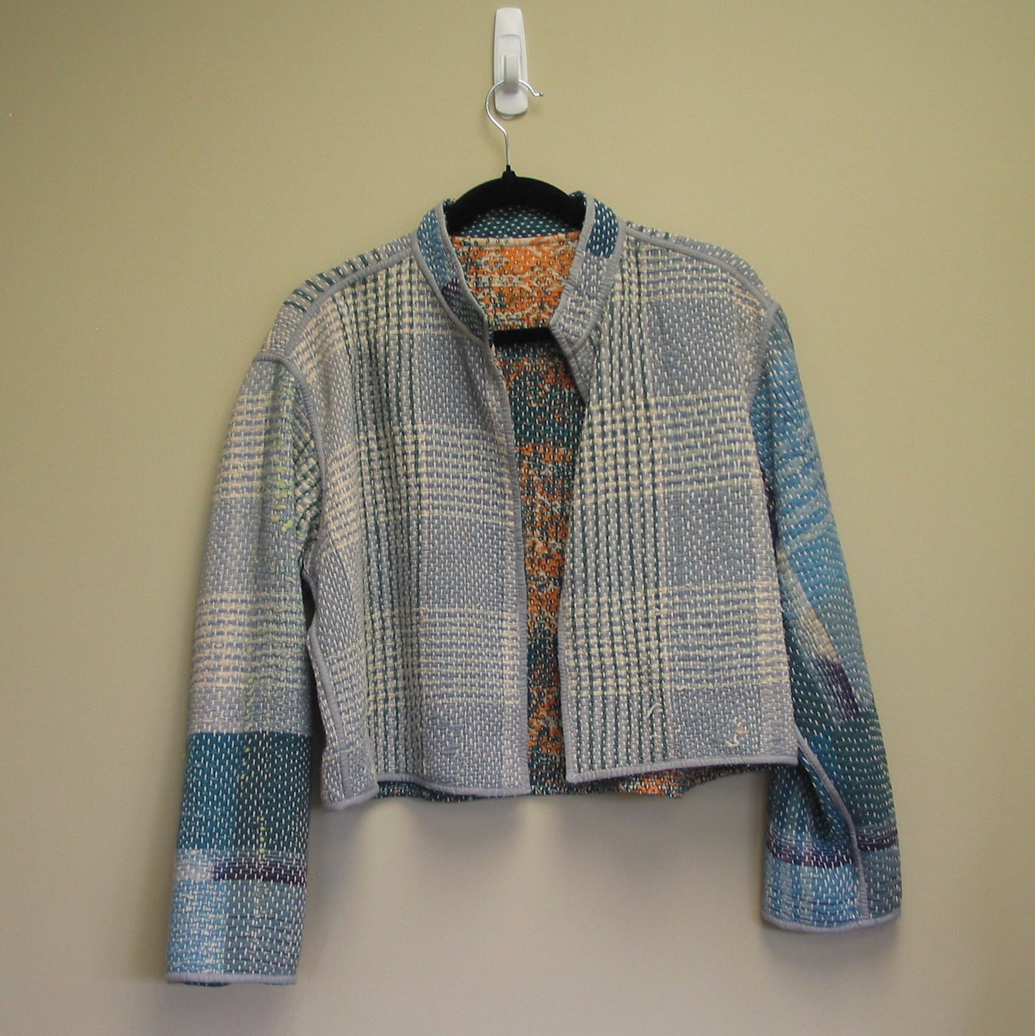 Plaid jacket on a hanger against a plain background