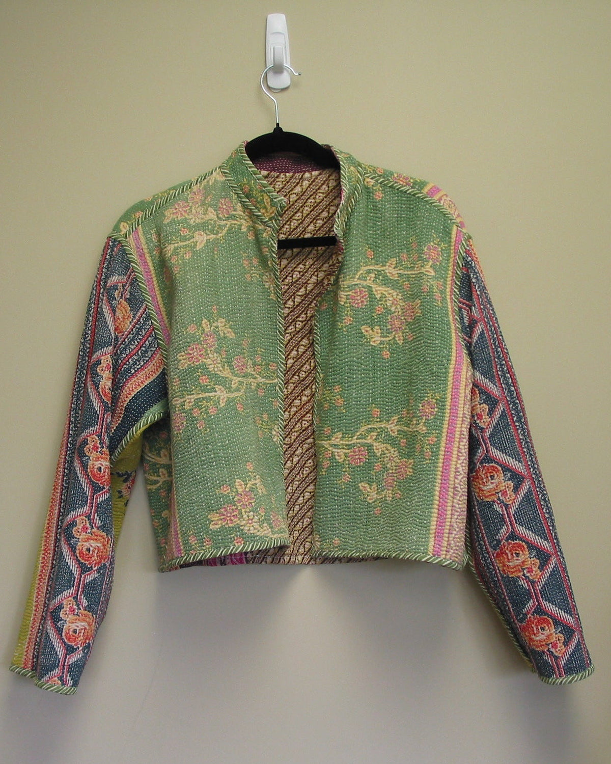 Embroidered jacket on a hanger against a plain background