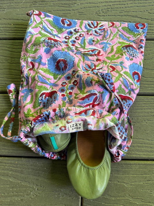 Floral-patterned bag with green shoes on a wooden surface