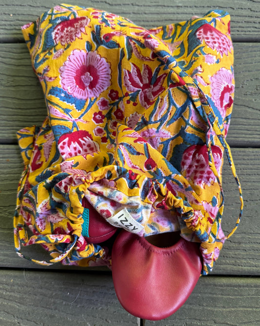 Colorful floral-patterned drawstring bag with a red object inside against a wooden background