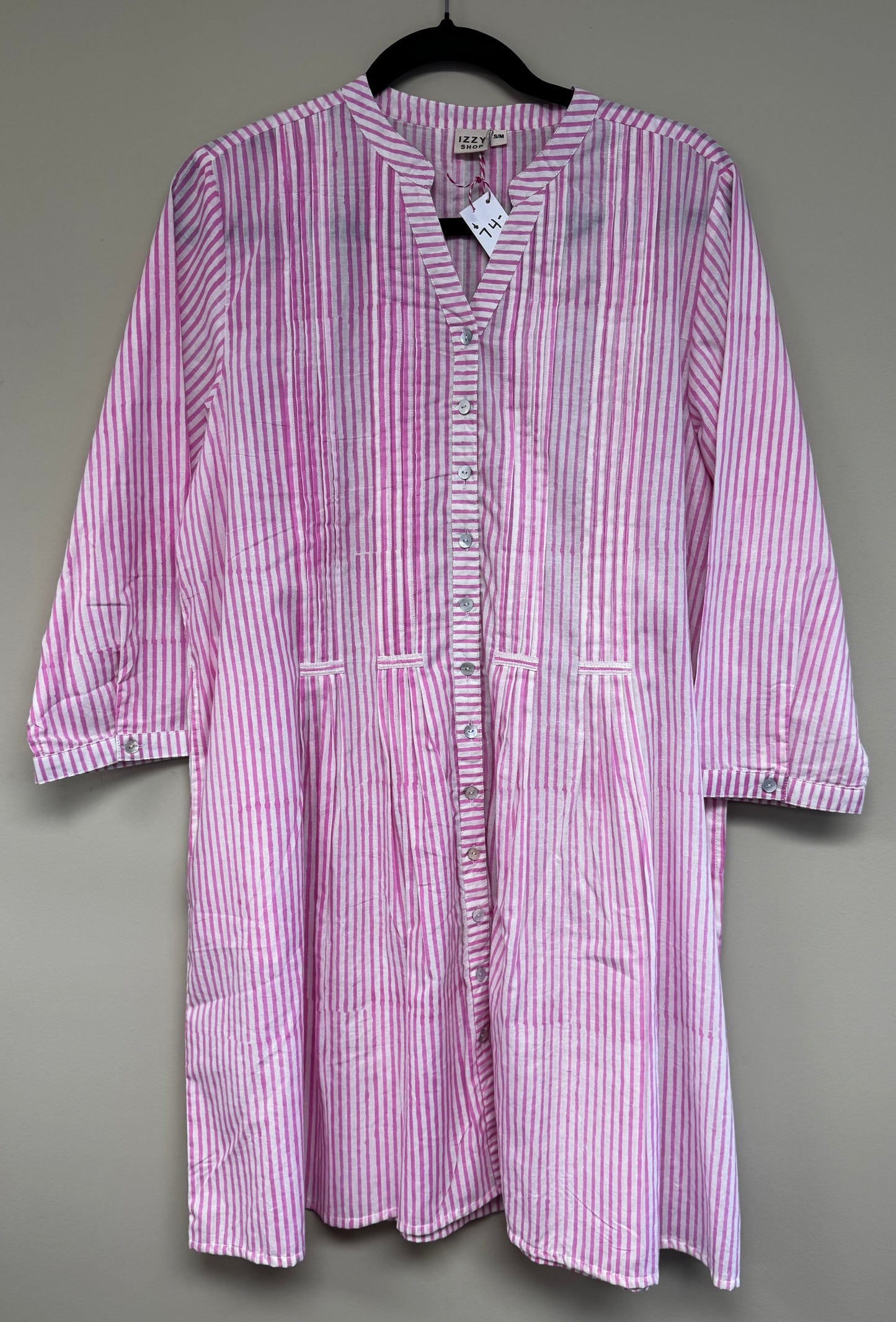 Pink and white striped dress on a hanger against a gray background