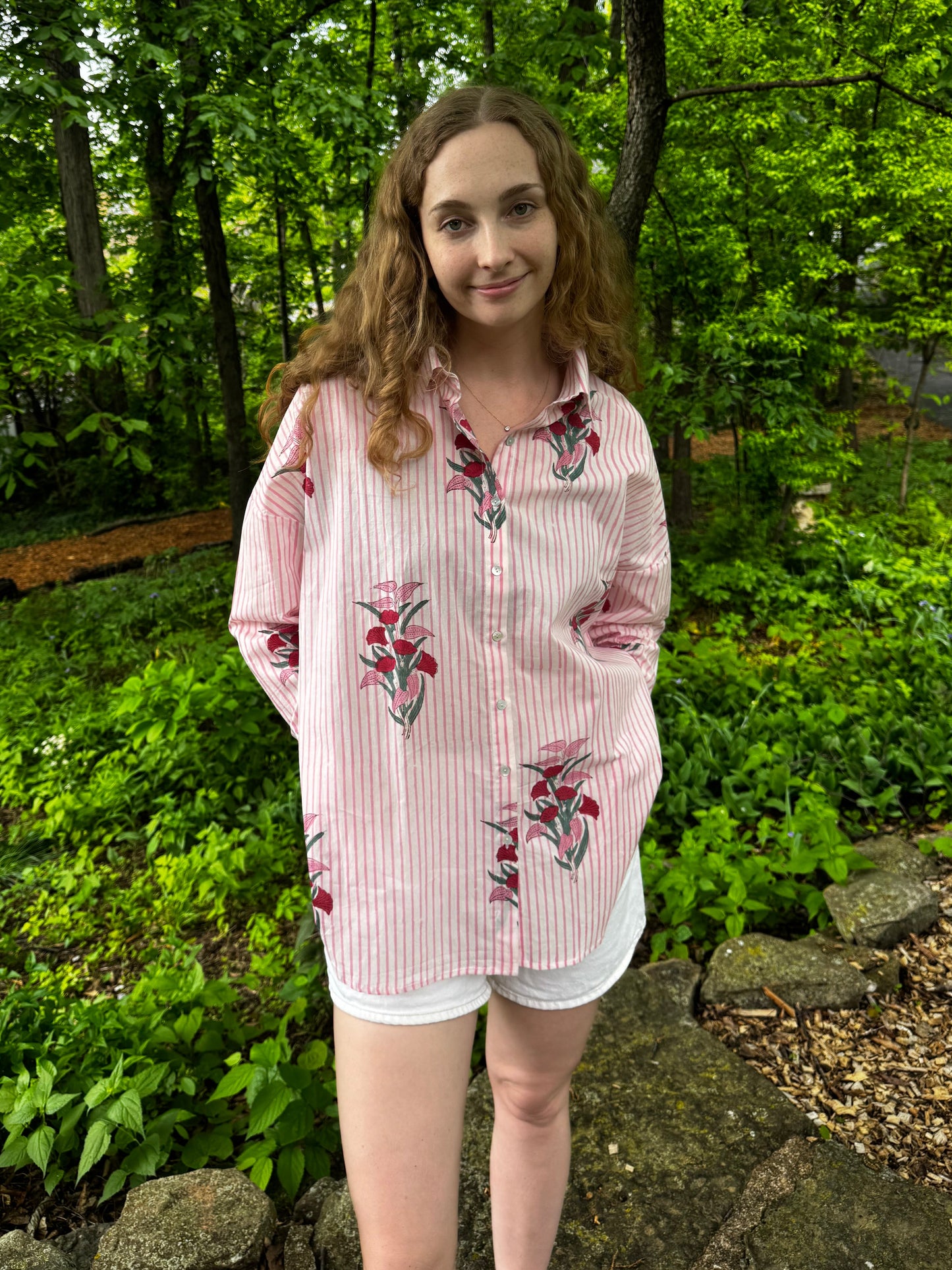 Person wearing a floral shirt standing in a forest