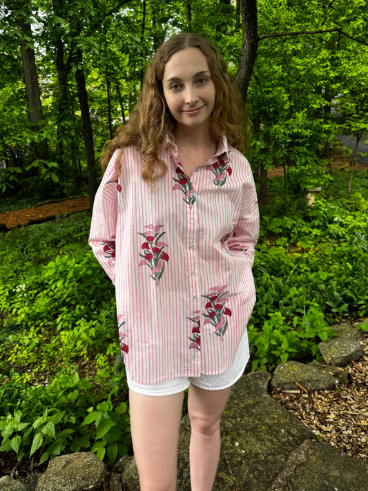 Person wearing a floral shirt standing in a forest