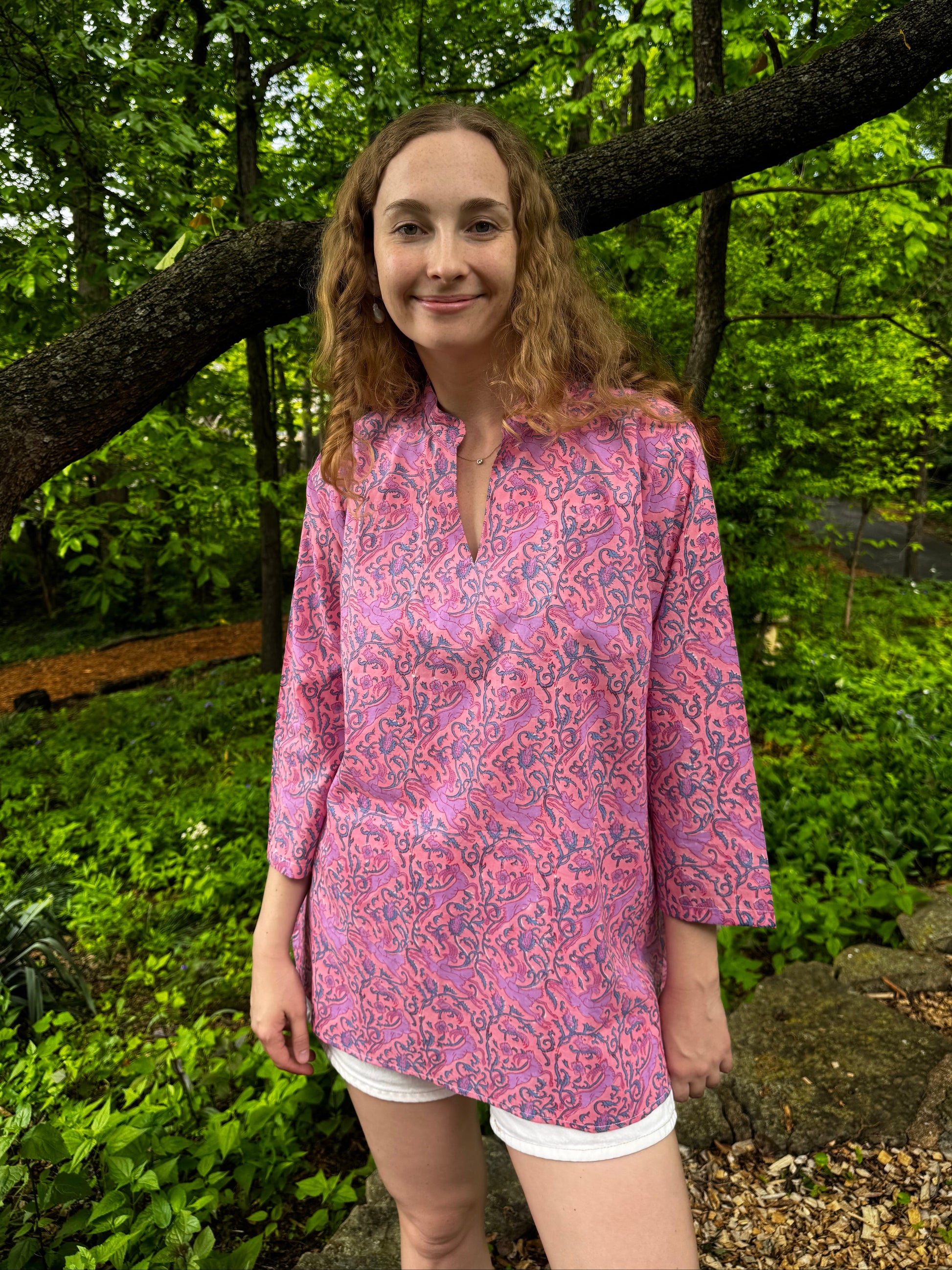 Person wearing a pink patterned dress standing in a forest