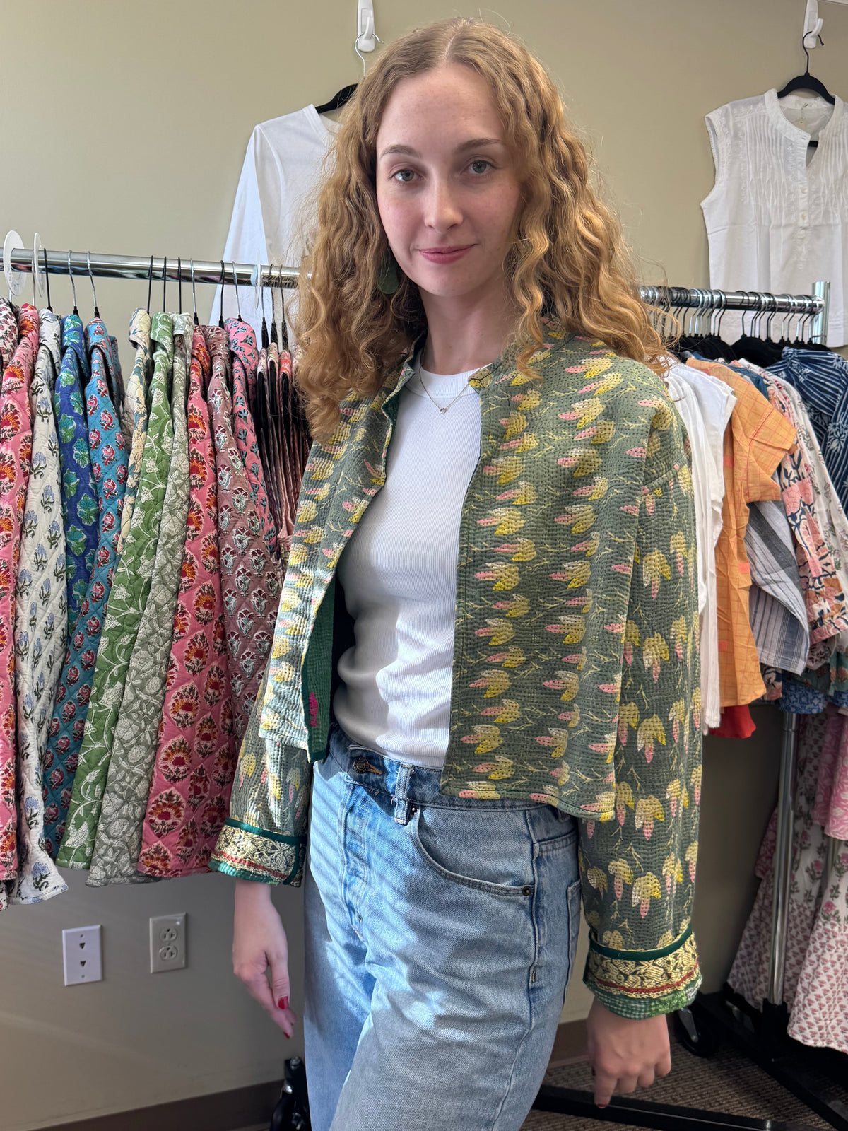 Woman standing in front of a rack of patterned clothes in a store.