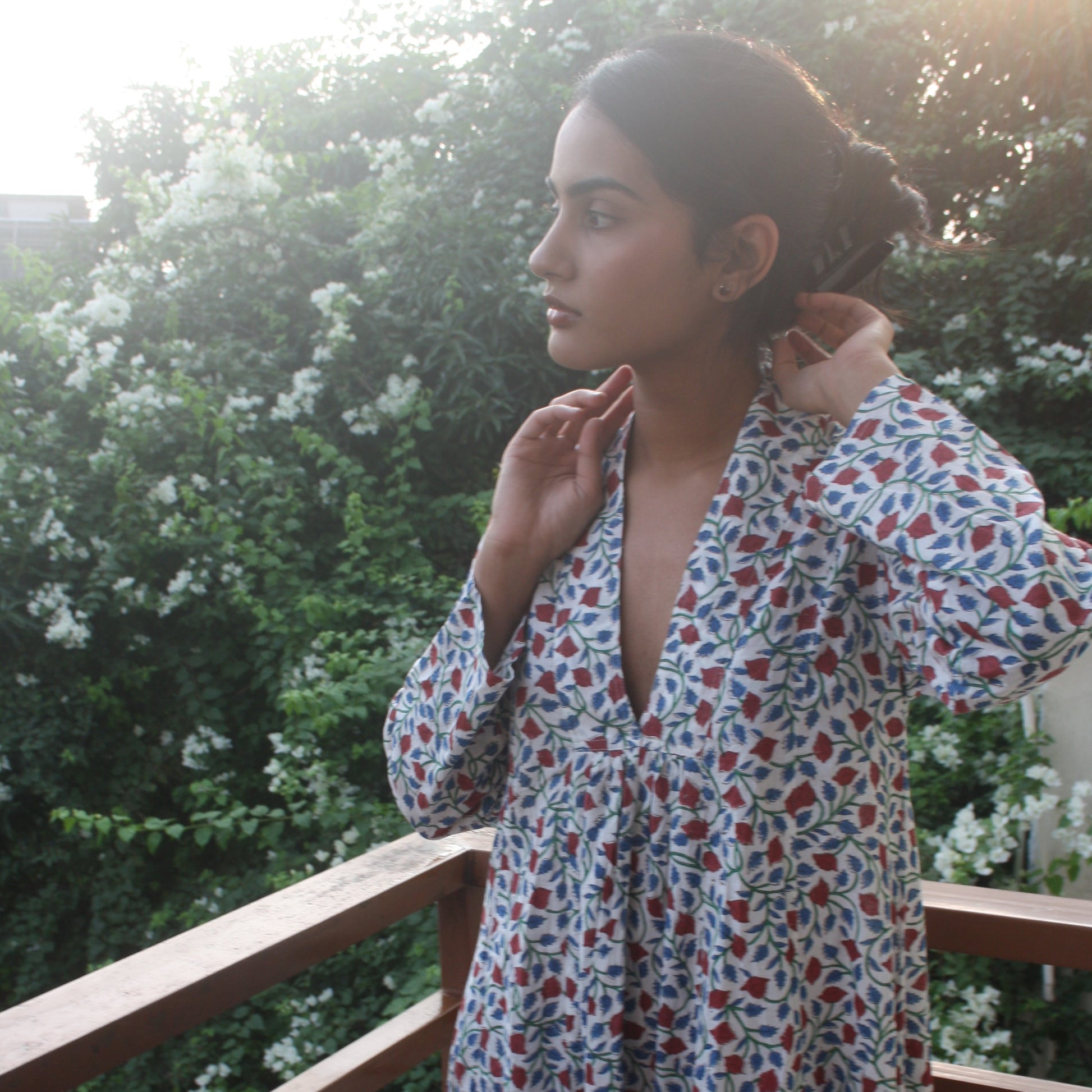 Woman wearing a floral dress standing outdoors with greenery in the background