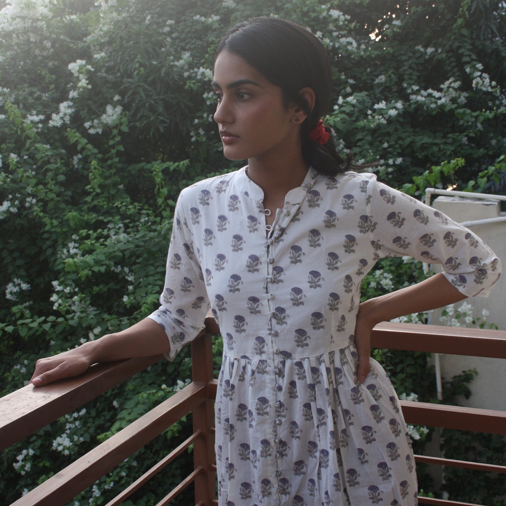 Woman in a floral dress standing outdoors with greenery in the background