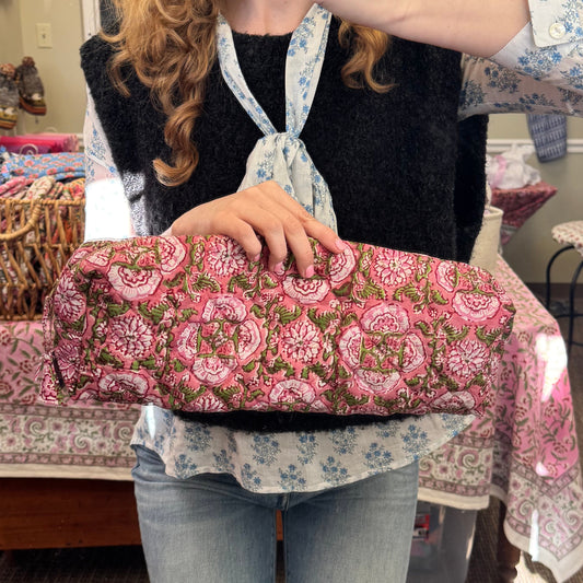 Person sitting on a floral-patterned chair in a room with a mirror reflecting their image.