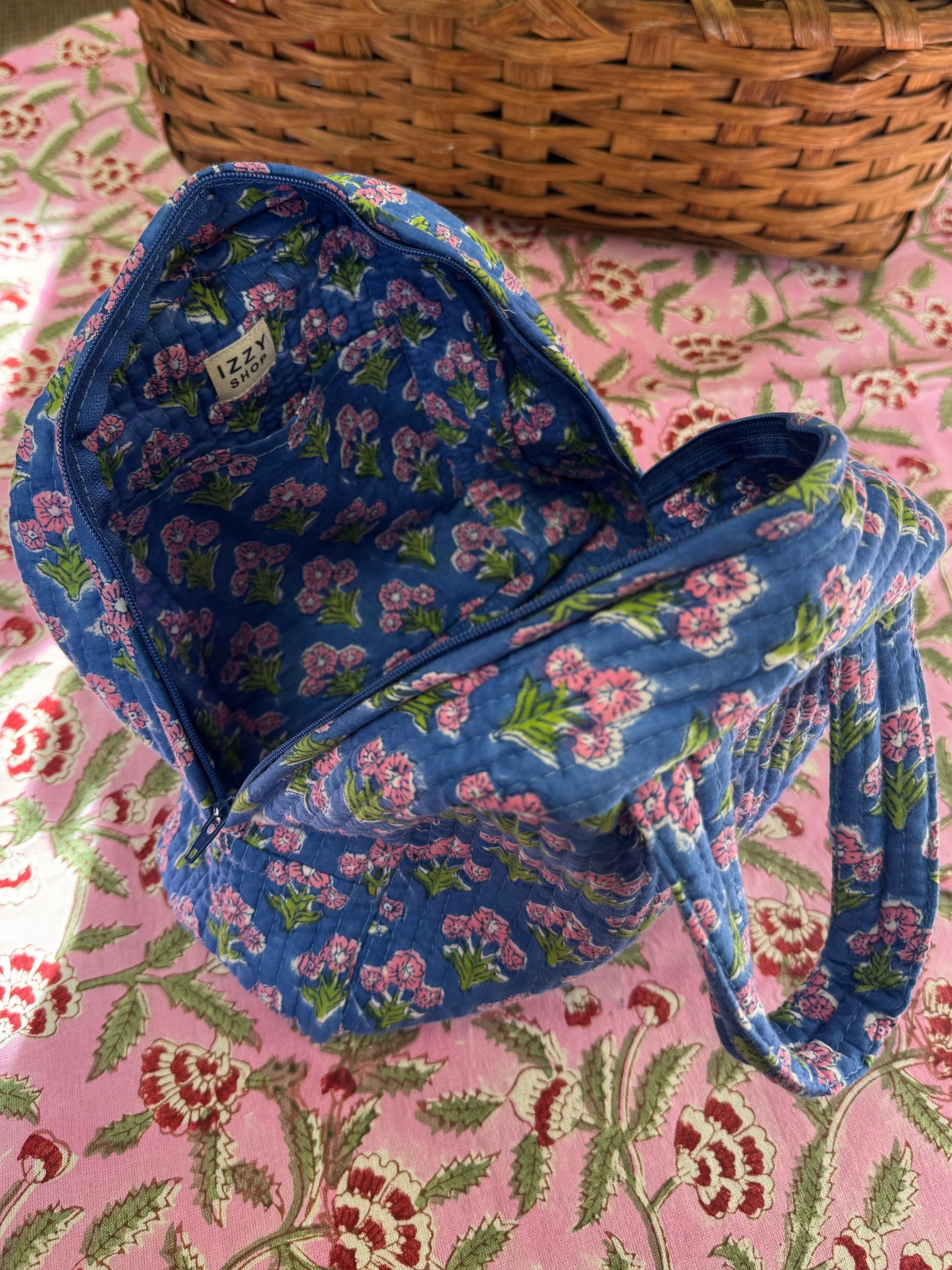 Blue floral-patterned bag on a pink floral fabric background